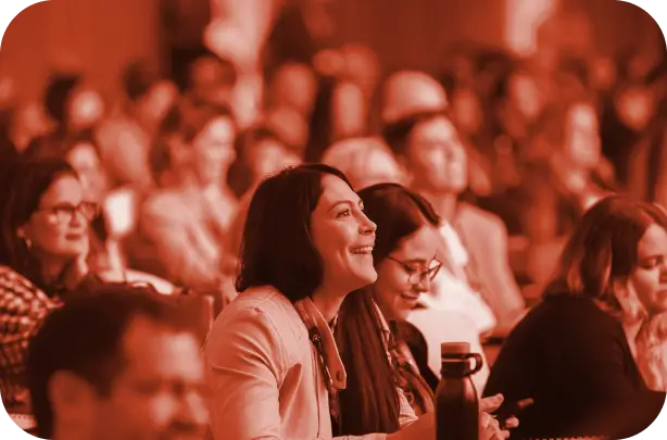 pessoas sorrindo assistindo uma palestra